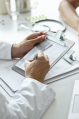 Doctor writing prescription on clipboard