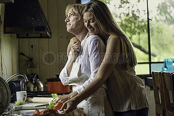Daughter embracing her mother in kitchen