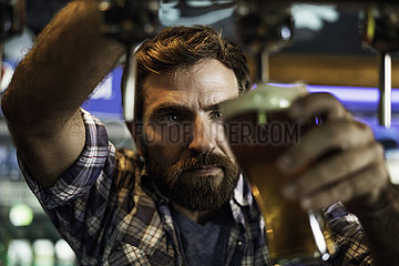 Man drawing beer from tap