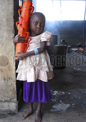 Portrait of a young girl carrying a stack of feeding cups at an MSF feeding centre in Angola. Feeding centres and other humanitarian aid were organised in Angola after widescale malnutrition during and following the countrys civil war.