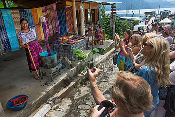 tourists watching native Maya woman colouring wool with natural dyes  Traditional handwoven mayan textile