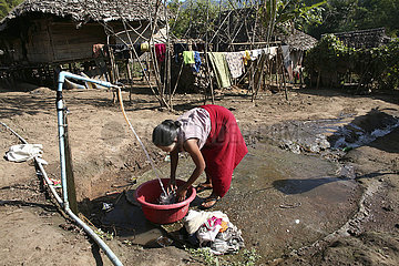 A Burmese woman washes clothes in the displaced person camp near the border with Thailand. In Myanmar (Burma)  thousands of people have settled near the border as a result of oppression in their homeland. Around 200 Burmese displaced people have settled i