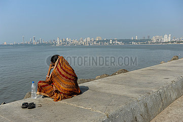 Mumbai  Indien  Frau sitzt an der Uferpromenade entlang der Marine Drive
