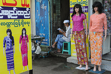 Yangon  Myanmar  Mann liest neben Schaufensterpuppen fuer Damenmode