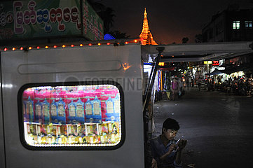 Yangon  Myanmar  Losverkaeufer auf Nachtmarkt mit Shwedagon-Pagode