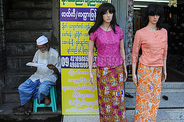 Yangon  Myanmar  Mann liest neben Schaufensterpuppen fuer Damenmode
