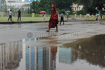Yangon  Myanmar  Buddhistischer Moench geht in der Regenzeit eine Strasse entlang