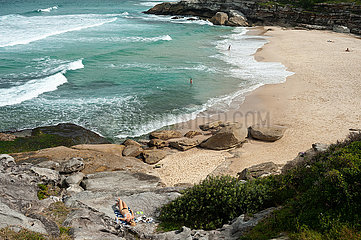 Sydney  Australien  Eine Frau sonnt sich auf den Felsen am Strand von Tamarama Beach