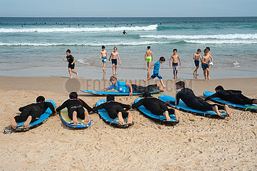 Sydney  Australien  Surfkurs mit Teilnehmern im Sand am Strand von Bondi Beach