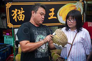 Singapur  Republik Singapur  Verkaeufer oeffnet frische Durian auf einem Strassenmarkt in Chinatown
