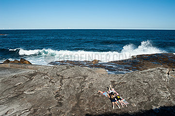 Sydney  Australien  Maedchen sonnen sich auf den Felsen am Tom Caddy Point