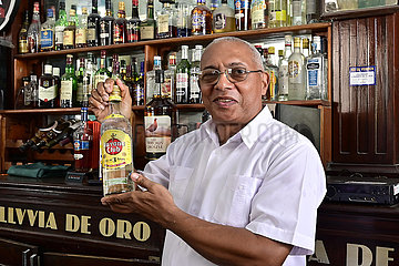 Cuba  Havanna - Barkeeper in der Altstad praesentiert eine Flasche Rum