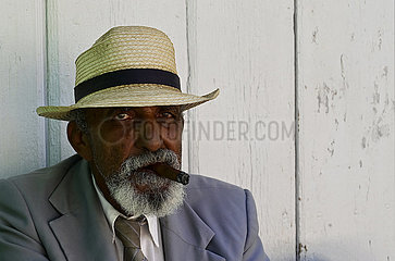 Kuba  Trinidad - Kubaner raucht eine Zigarre vor seinem Haus