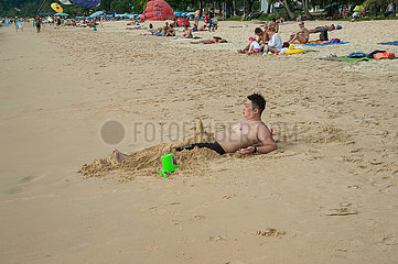 Phuket  Thailand  Asiatischer Urlauber liegt am Strand von Karon Beach im Sand