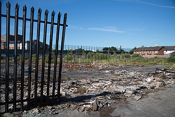 Grossbritannien  Nordirland  Belfast - Protestantischer Teil von West Belfast - verwahrloster  verbrannter Platz nach dem bonfire vom Orangemens Day  hinten der Peace Wall