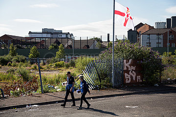 Grossbritannien  Nordirland  Belfast - Protestantischer Teil von West Belfast - verwahrloster  verbrannter Platz nach dem bonfire vom Orangemens Day mit Ulster Flagge