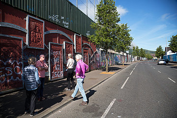 Grossbritannien  Nordirland  Belfast - Protestantischer Teil von West Belfast (Cupar Way)  Fremdenfuehrer mit Touristen am Peace Wall  der Stadtteil nach Konfession teilt