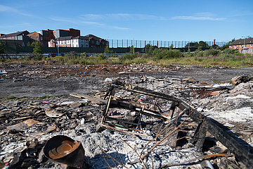 Grossbritannien  Nordirland  Belfast - Protestantischer Teil von West Belfast - verwahrloster  verbrannter Platz nach dem bonfire vom Orangemens Day  hinten der Peace Wall