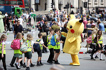 London  Grossbritannien  Schulkinder klatschen sich auf einer Strasse mit der Pokemon-Figur Pikachu ab