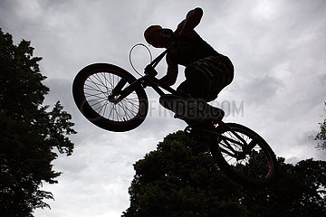 Berlin  Deutschland  Teenanger fliegt mit seinem BMX-Rad durch die Luft