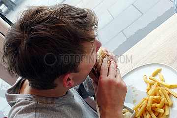 Berlin  Deutschland  Junge isst einen Hamburger mit Pommes Frites