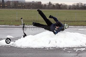 Berlin  Deutschland  Junge faellt im Winter von seinem Roller auf einen Schneehaufen