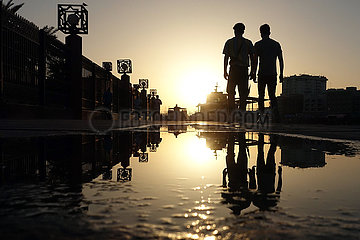 Dubai  Vereinigte Arabische Emirate  Jugendliche spiegeln sich bei Sonnenuntergang in einer Pfuetze