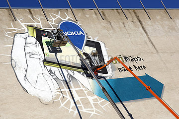 Berlin  Deutschland  Maenner kleben ein riesiges Werbeplakat der Firma Nokia an eine Hauswand
