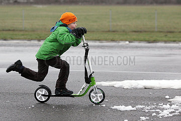 Berlin  Deutschland  Junge faehrt im Winter mit seinem Roller ueber das Tempelhofer Feld