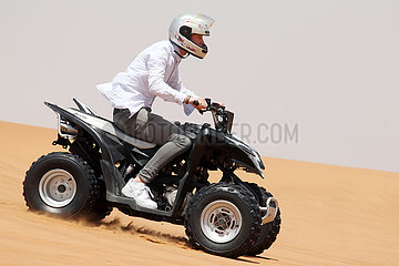 Dubai  Vereinigte Arabische Emirate  Jugendlicher faehrt auf einem Quad durch die Wueste