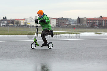 Berlin  Deutschland  Junge faehrt im Winter mit seinem Roller ueber das Tempelhofer Feld