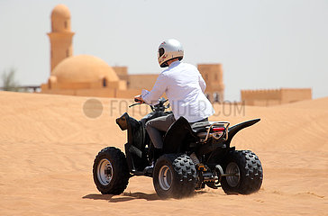 Dubai  Vereinigte Arabische Emirate  Jugendlicher faehrt auf einem Quad durch die Wueste