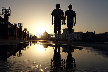 Dubai  Vereinigte Arabische Emirate  Jugendliche spiegeln sich bei Sonnenuntergang in einer Pfuetze