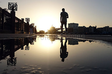 Dubai  Vereinigte Arabische Emirate  Jugendlicher spiegelt sich bei Sonnenuntergang in einer Pfuetze