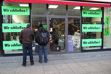 Berlin  Deutschland  Maenner stehen vor einem insolventen Ladengeschaeft