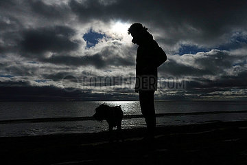Braenna  Schweden  Silhouette  Junge geht mit seinem Hund am Strand spazieren