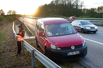 Hamburg  Deutschland  Frau steht bei einer Autopanne auf der A24 hinter der Leitplanke und schaut auf ihr Mobiltelefon