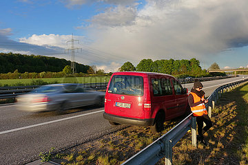 Hamburg  Deutschland  Frau steht bei einer Autopanne auf der A24 hinter der Leitplanke und schaut auf ihr Mobiltelefon