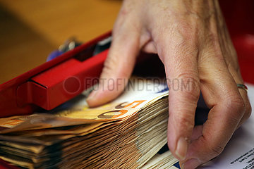 Halle (Saale)  Deutschland  Hand greift nach 50-Euroscheinen in einer Geldkassette