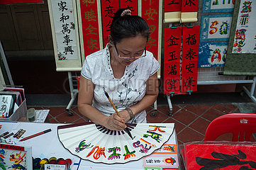 Singapur  Republik Singapur  Eine Kalligraphin verziert einen Handfaecher mit chinesischen Schriftzeichen und Bildern