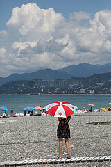 Batumi  Georgien  Frau steht mit einem Regenschirm in den Nationalfarben von Georgien am Strand