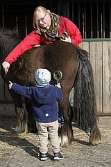 Dierhagen  Kleinkind putzt zusammen mit seiner Mutter ein Pony