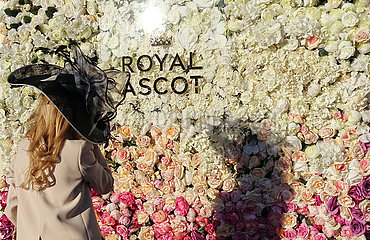 Ascot  Grossbritannien  elegant gekleidete Frau mit Hut steht bei der Rennwoche Royal Ascot vor einer Wand aus Rosen