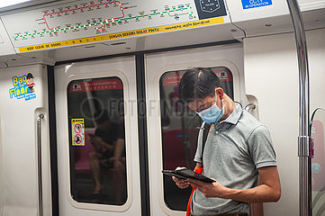 Singapur  Republik Singapur  Ein Mann mit Mundschutz in einer U-Bahn