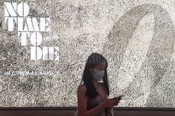 Singapur  Republik Singapur  Frau mit Mundschutz vor einer Werbung fuer James Bond Film