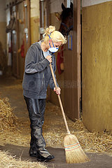 Neuenhagen  Pferdepflegerin traegt bei der Stallarbeit zum Schutz vor dem Coronavirus eine Atemschutzmaske