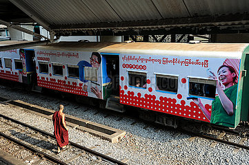 Yangon  Myanmar  Buddhistischer Moench und Nahverkehrszug am Bahnsteig des Hauptbahnhofs