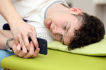 Berlin  Deutschland  Teenager tippt im Bett auf seinem Smartphone herum