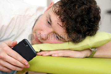 Berlin  Deutschland  Teenager schaut im Bett auf sein Smartphone