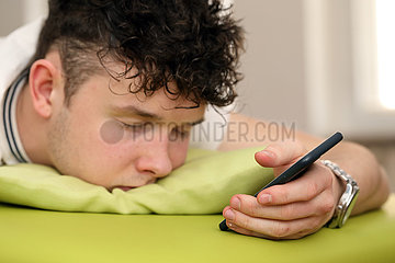 Berlin  Deutschland  Teenager ist im Bett beim Chatten auf seinem Smartphone eingeschlafen